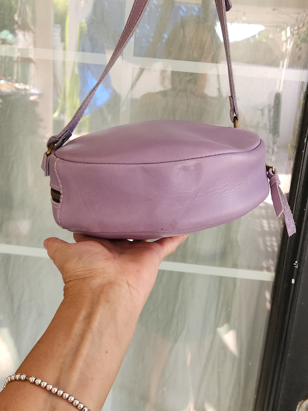 The purple round bag in the image is a Circle Crossbody in the color Lavender - Picture 3 of 8